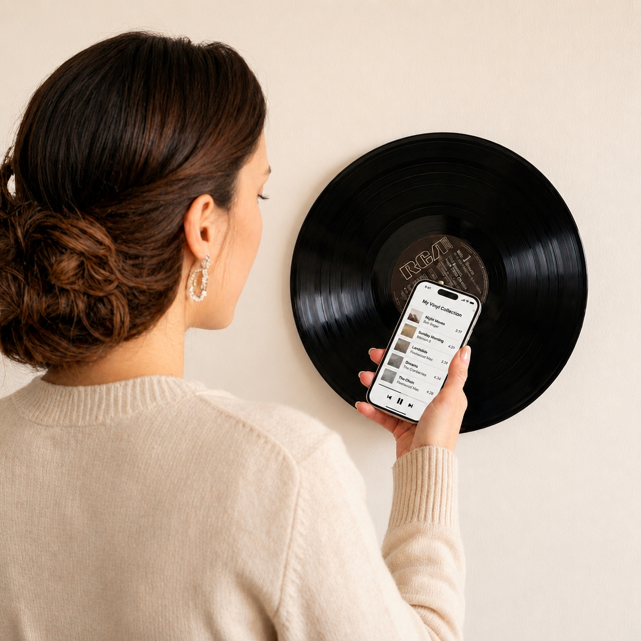 Woman holding a smartphone near a wall-mounted vinyl record to activate hidden NFC, showing a playlist on the phone screen and demonstrating the Melsphera CentreMount vinyl record wall display.